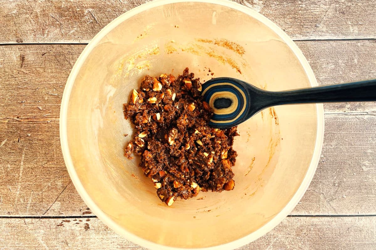 Plum crumble topping in bowl with wooden spoon.