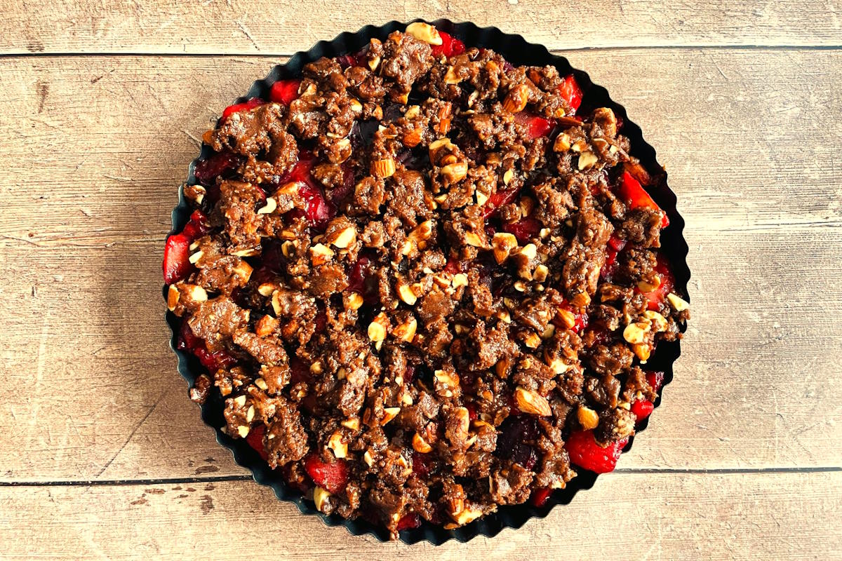 Unbaked plum crumble in baking dish.