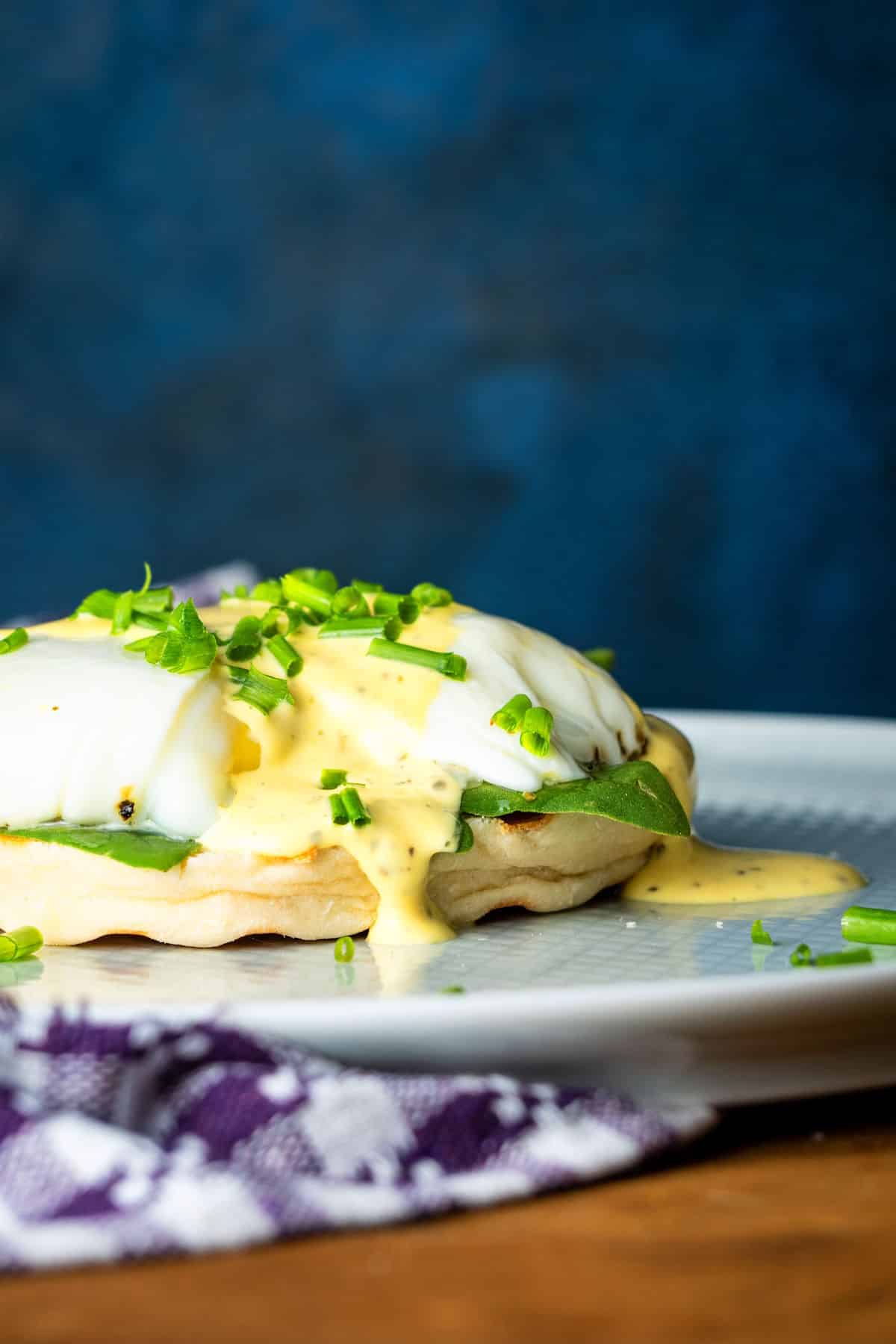 Poached egg on an English muffin with mock bearnaise sauce on white plate.