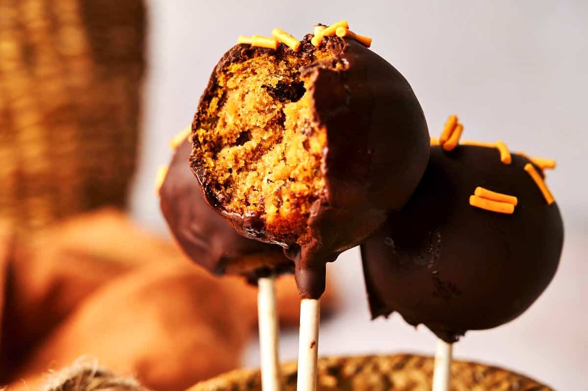 Pumpkin cake pop with a bite out of it.