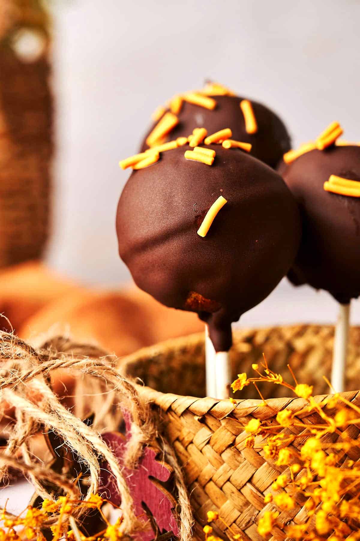 Pumpkin cake pops in small woven basket.