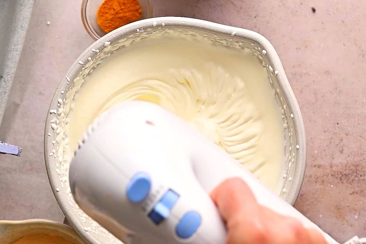 Whipped cream in bowl with electric mixer.
