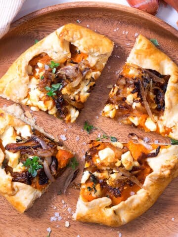 Pumpkin galette sliced into quarters on wooden plate.