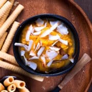 Pumpkin pie dessert hummus in black bowl with sweet biscuits on the side.