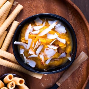 Pumpkin pie dessert hummus in black bowl with sweet biscuits on the side.