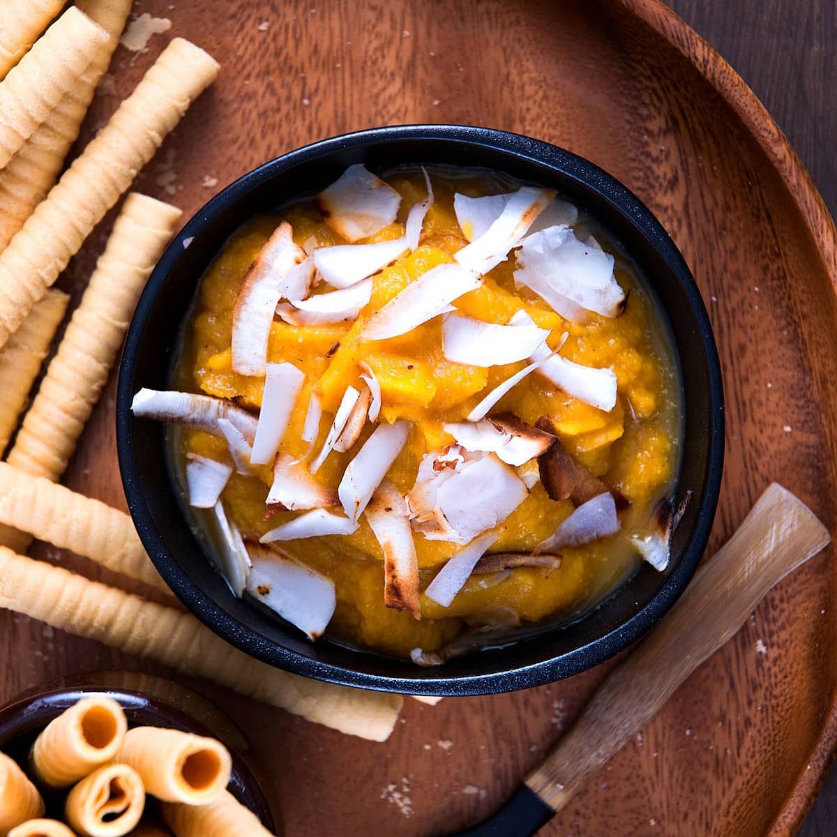 Pumpkin pie dessert hummus in black bowl with sweet biscuits on the side.