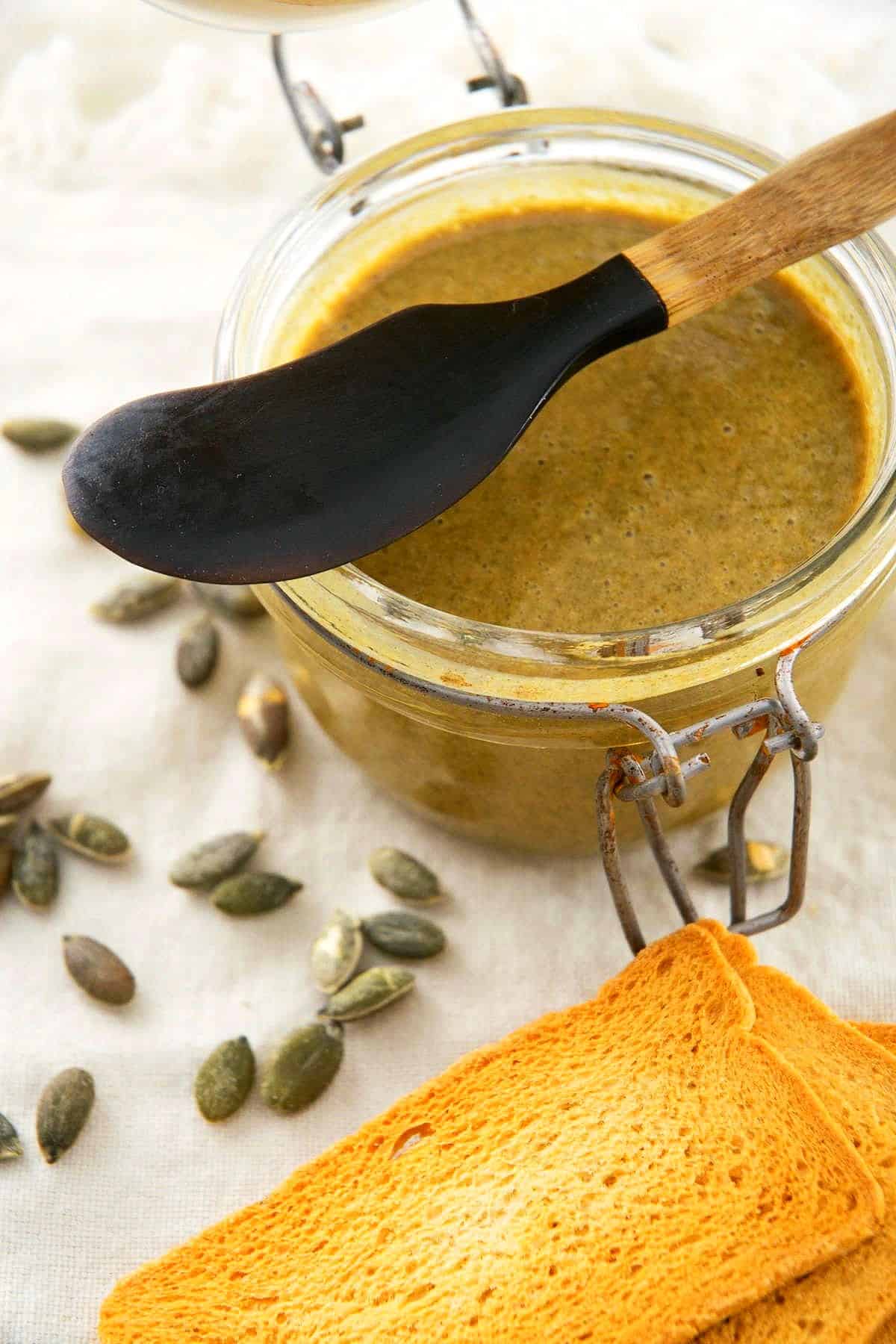 Pumpkin seed butter in a jar with crackers on the side.