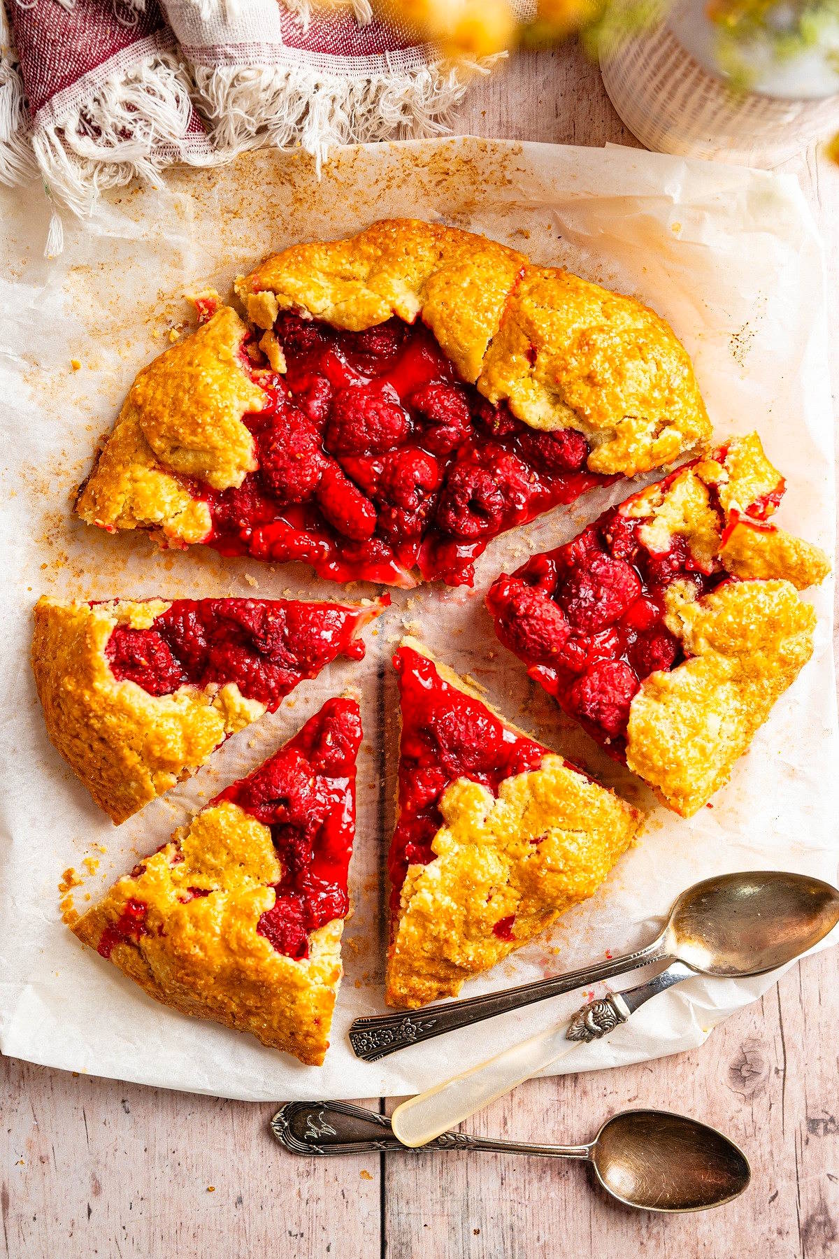 Raspberry galette sliced on parchment paper.
