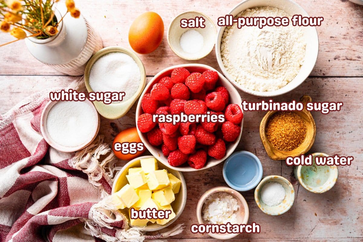 Raspberry galette ingredients labelled on light wooden background.