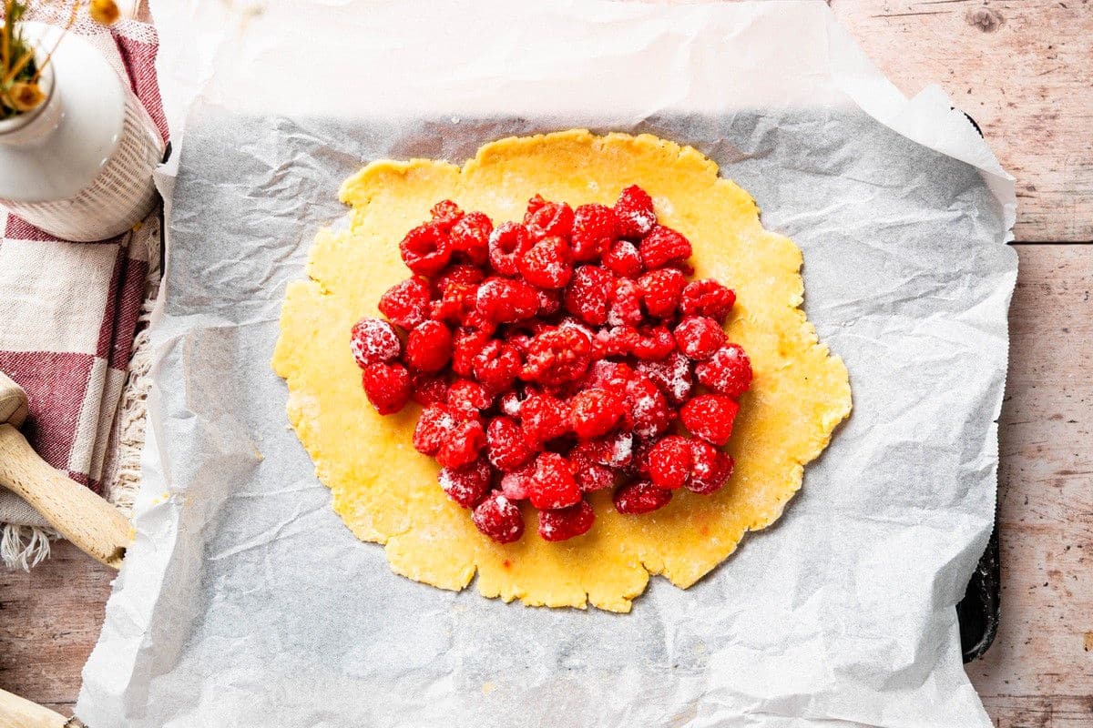 Galette pastry rolled out with raspberries in the center.