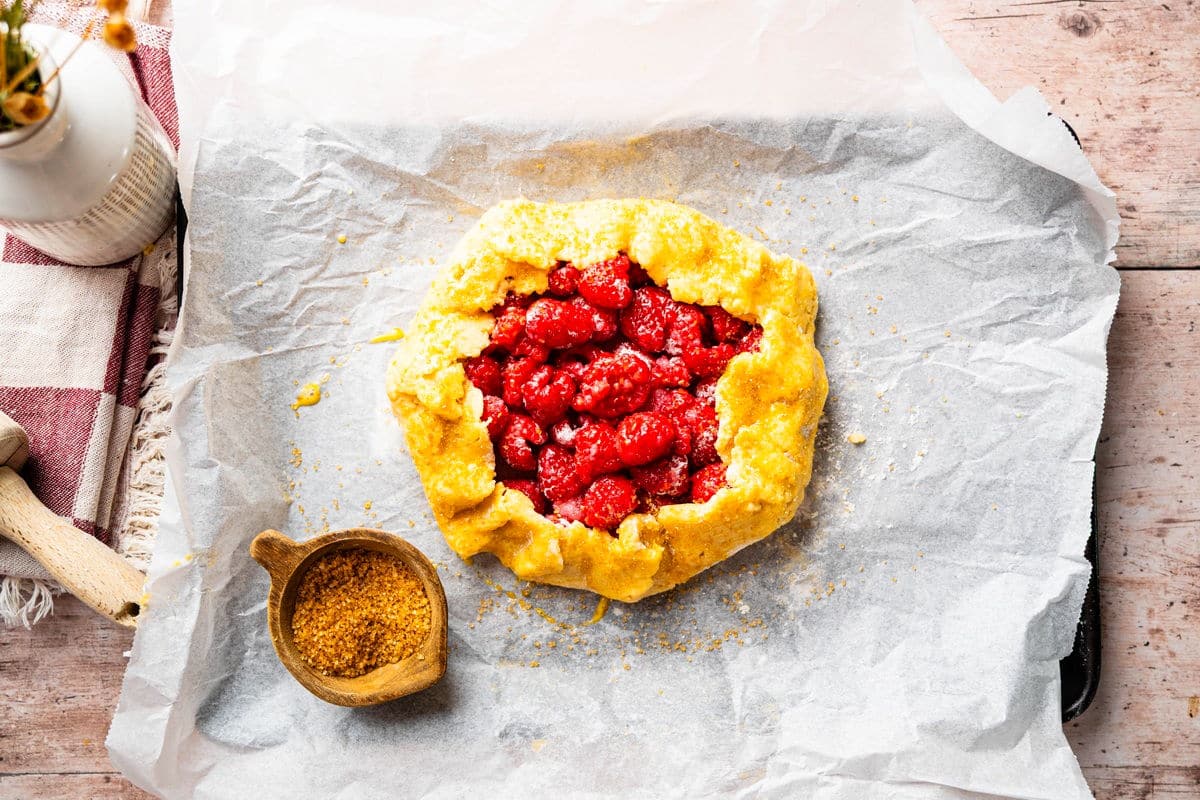 Unbaked raspberry galette sprinkled with turbinado sugar.