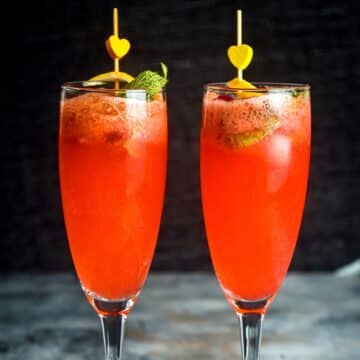 Raspberry twist cocktail in champagne glasses with lemon twist.