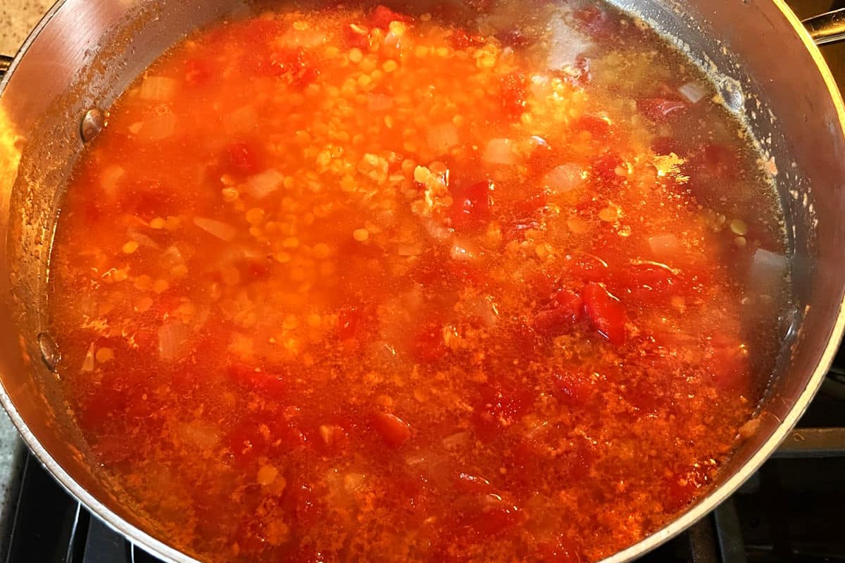 Red lentil soup simmering in pot.
