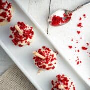 Red velvet cake pops in white dish on white wooden background.