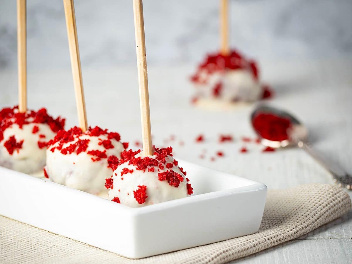 Red velvet cake pops in white dish.