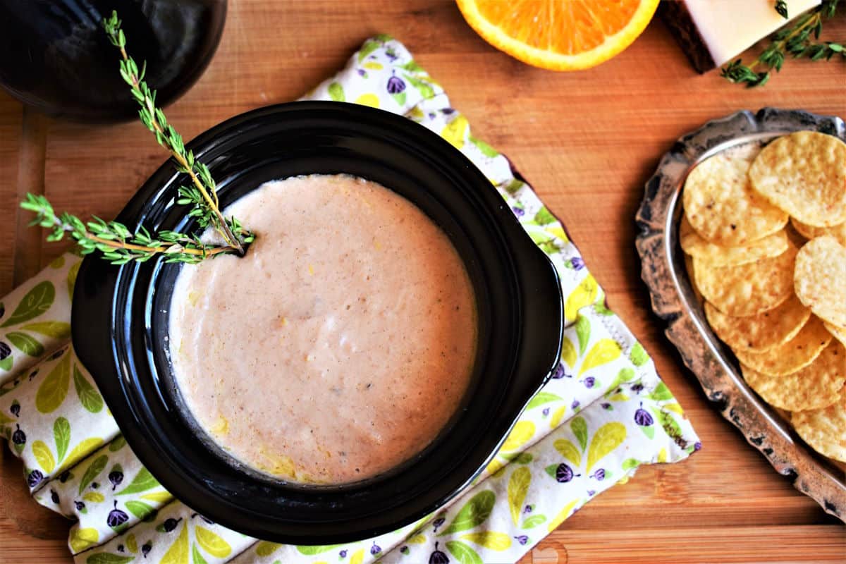 Red wine cheese dip in mini slow cooker with tortilla chips on the side.