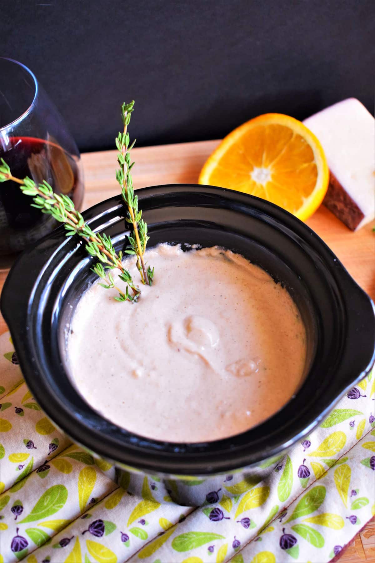 Red wine cheese dip in mini slow cooker on pot holder.