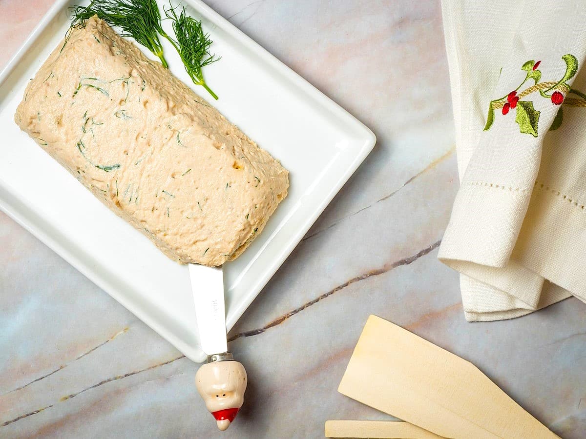 Salmon and dill mousse on a white dish with small santa knife.