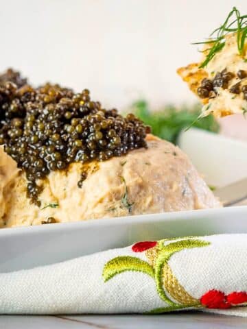 Salmon and dill mousse with caviar in white dish.