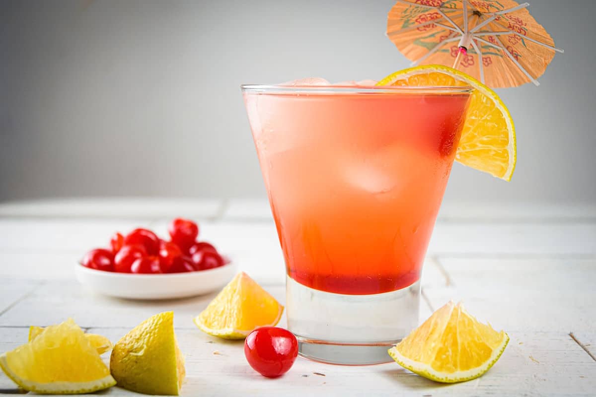Shirley temple in glass with orange garnish and umbrella.