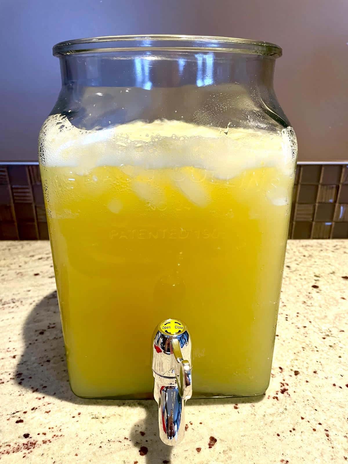 Ice, orange juice and 7-Up in glass dispenser.