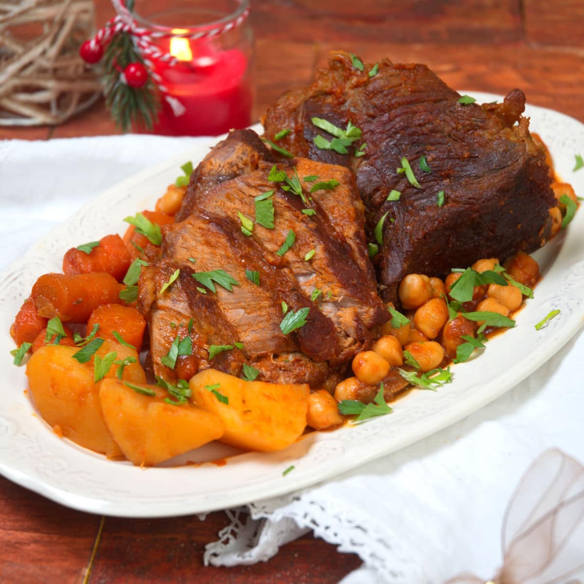 Sliced bison roast on white serving dish with vegetables.