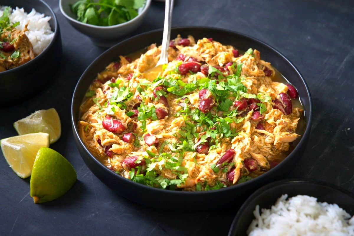 Mexican shredded chicken with salsa verde in dark bowl with spoon.
