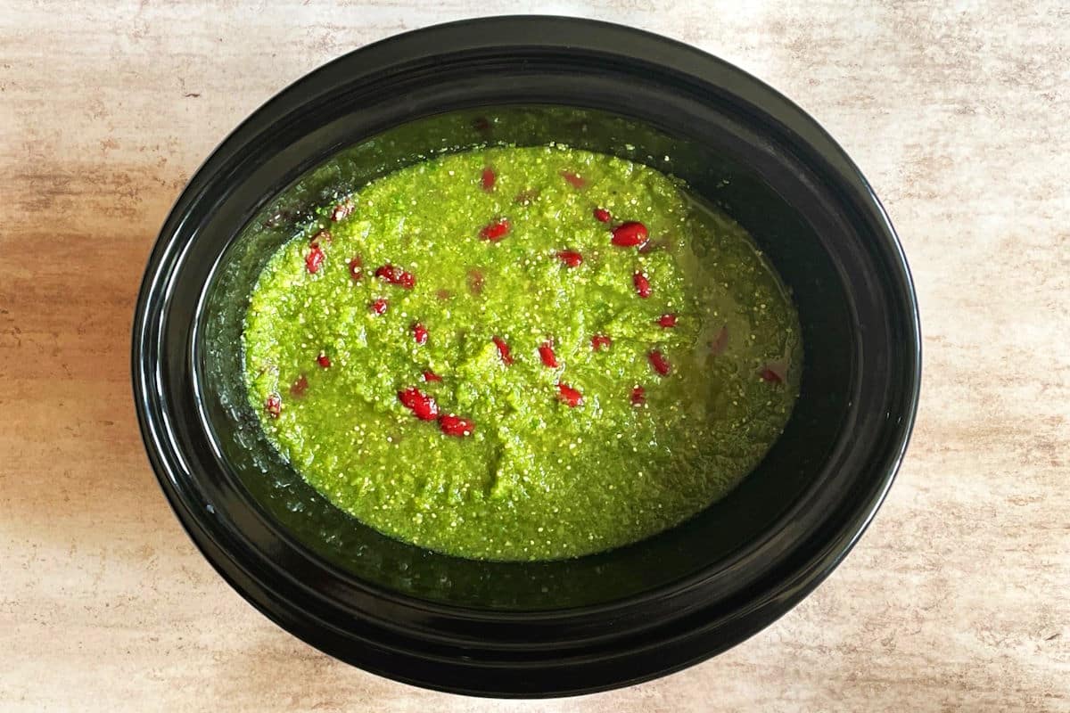 Raw chicken breasts with salsa verde and beans in slow cooker.