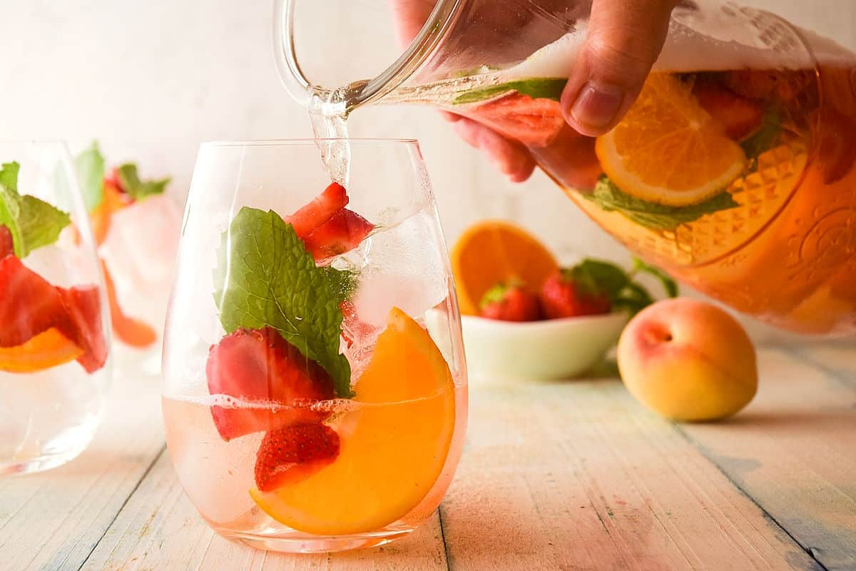 Spring white wine sangria in glass and pitcher with mint.