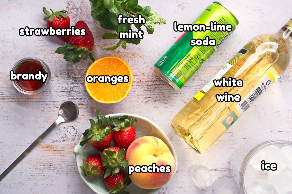 Spring white wine sangria ingredients prepped on light wooden background.