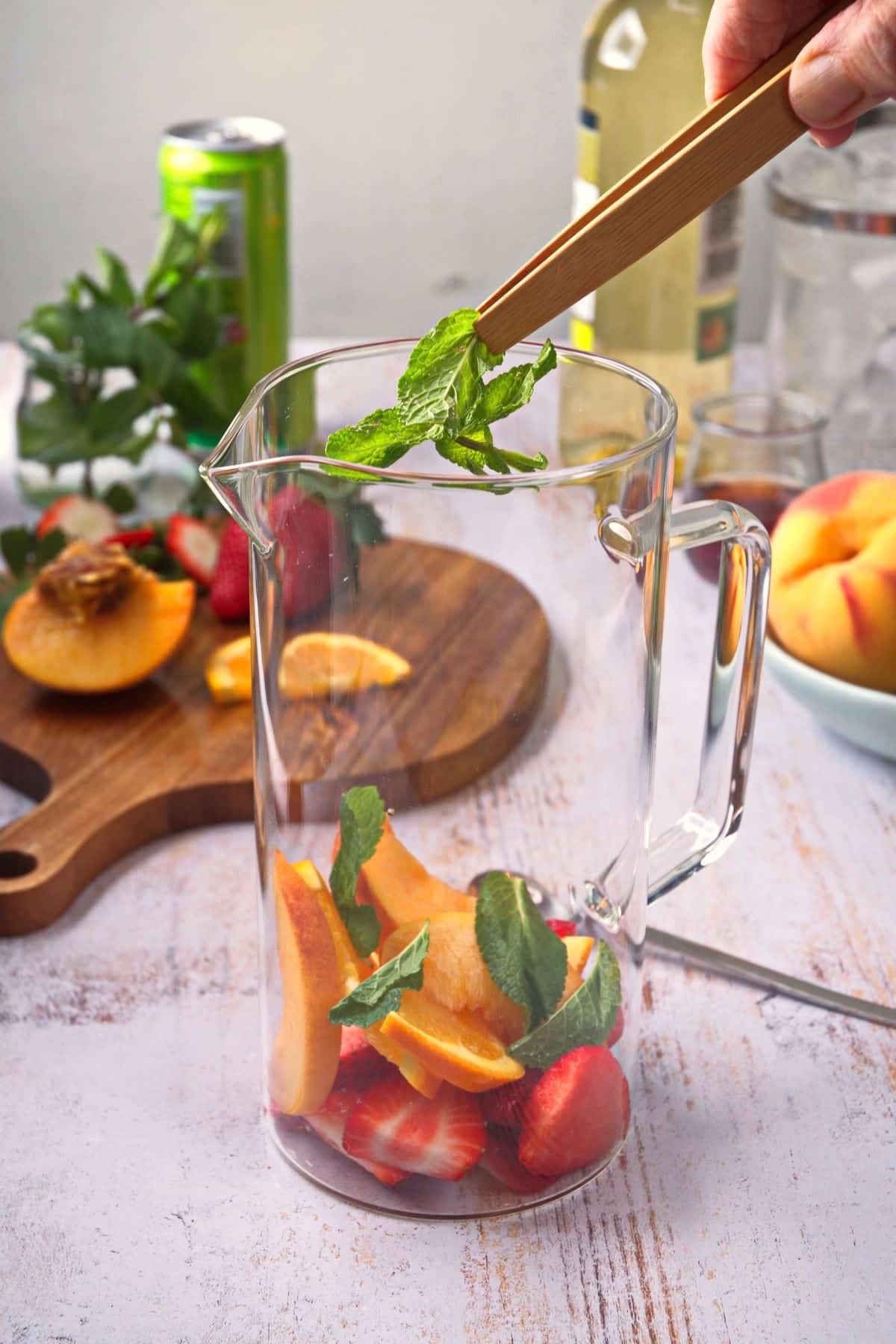 Fresh fruit and mint added to glass pitcher.