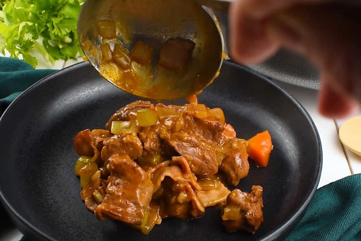 Beef stew ladled onto black plate.