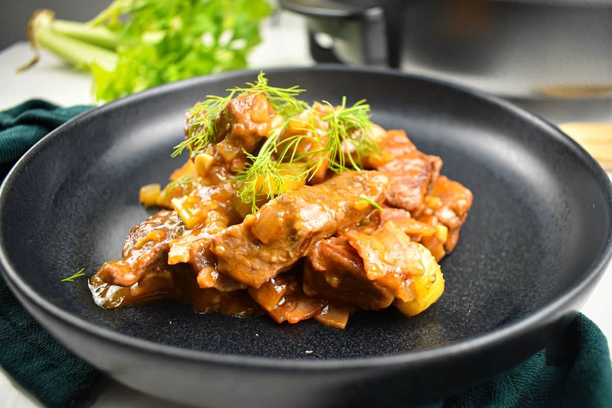 Beef black beer stew on black plate.