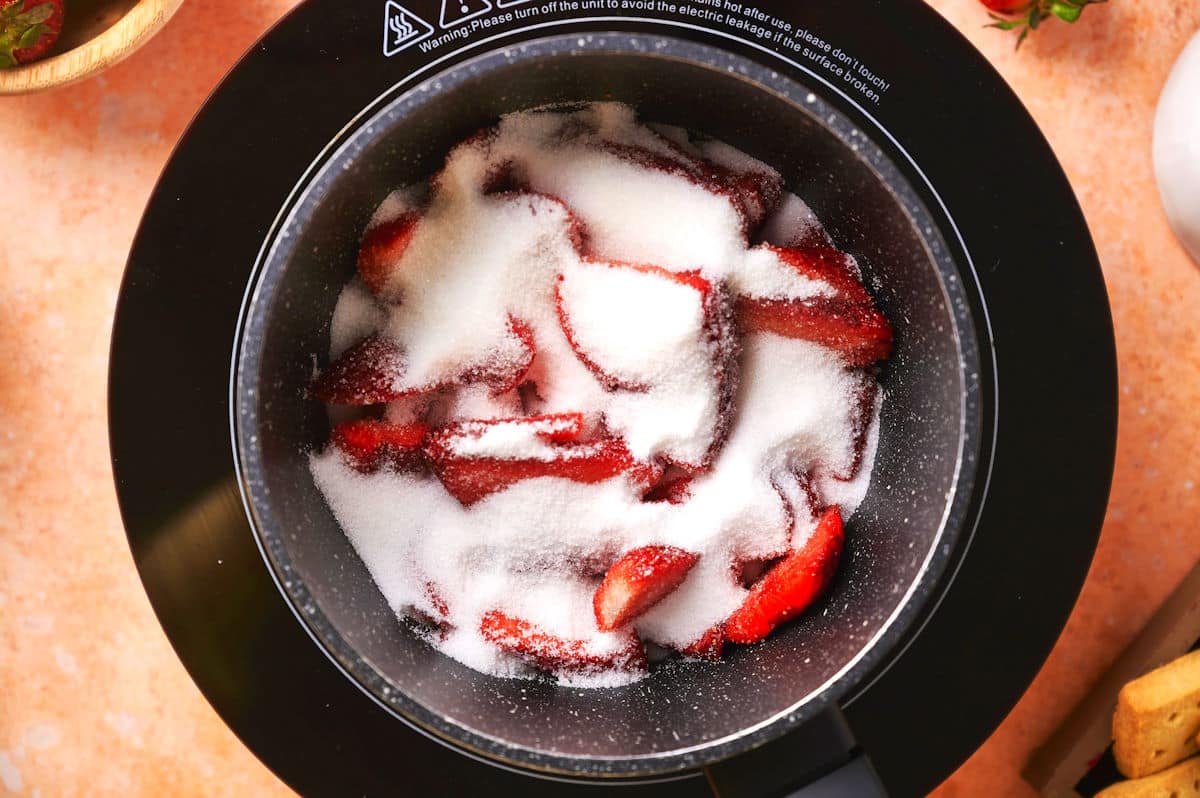 Strawberries and sugar in saucepan.