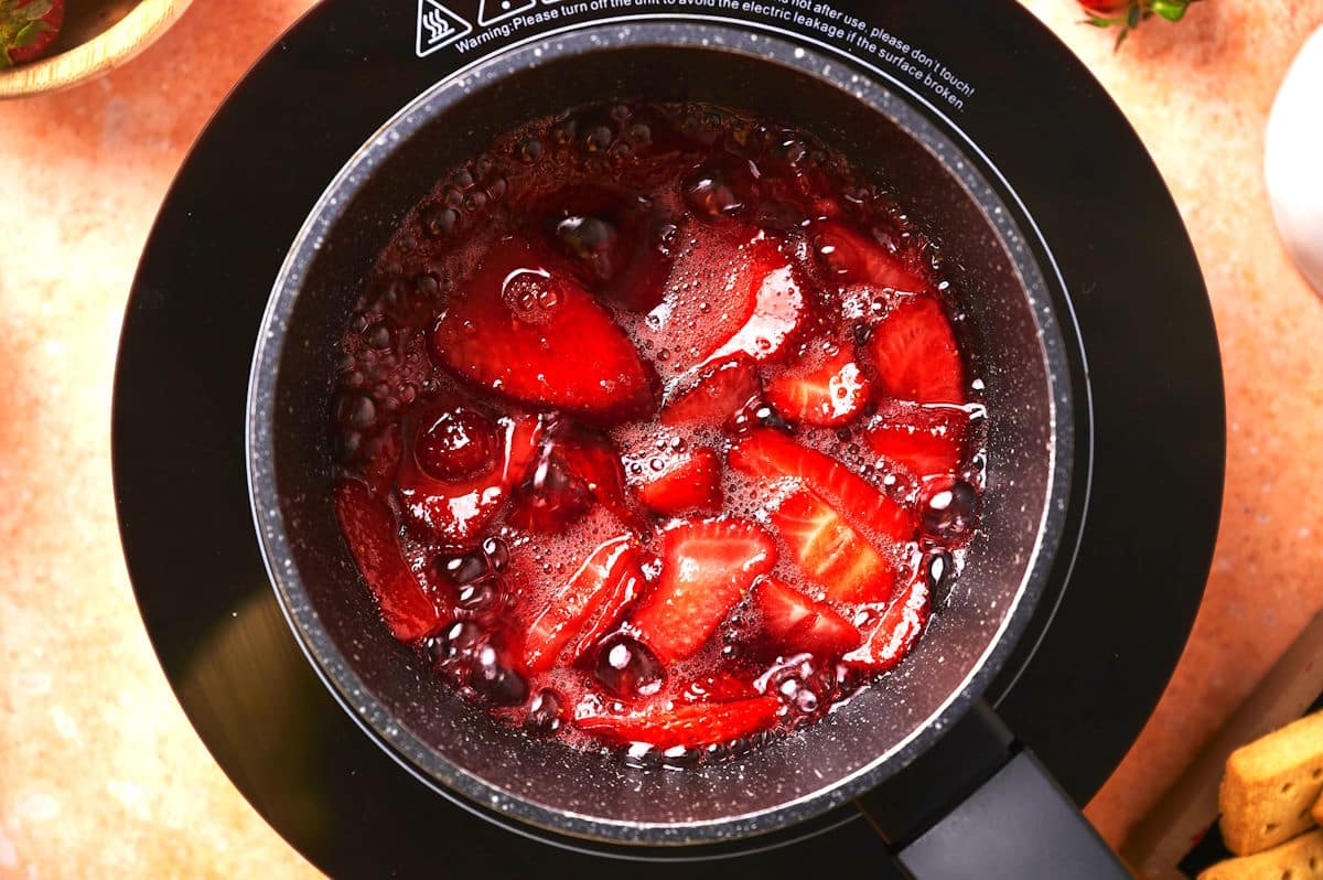 Strawberries and sugar simmering in saucepan.