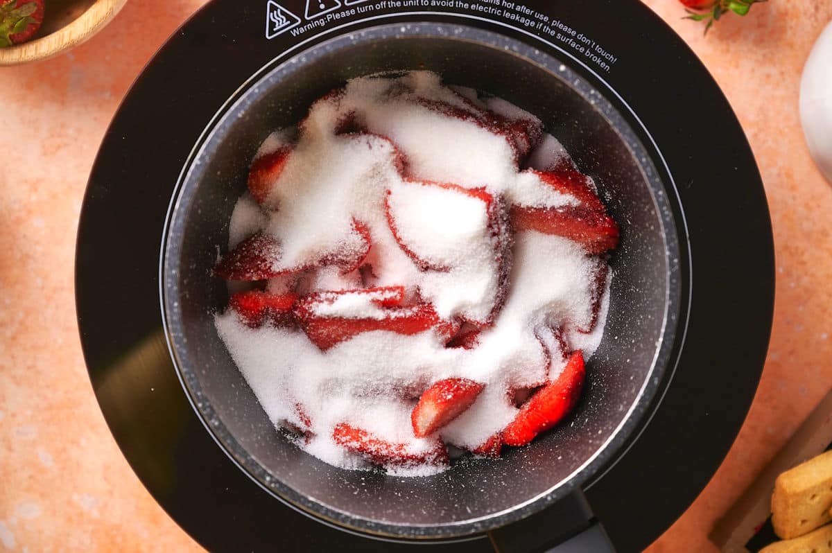 Strawberries and sugar in pot.