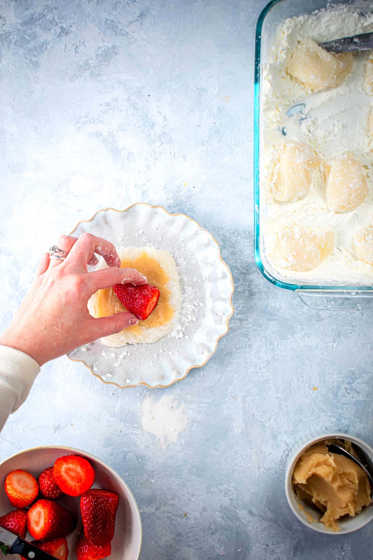 Mochi strawberry getting assembled on white plate.