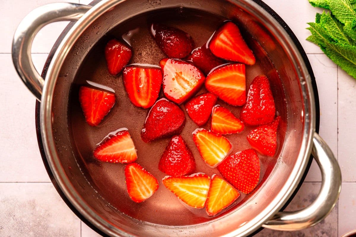 Strawberries, sugar and water heating in pot.
