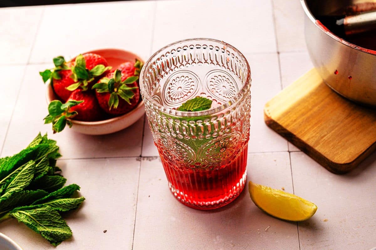 Glass with mint, lime and strawberry syrup.