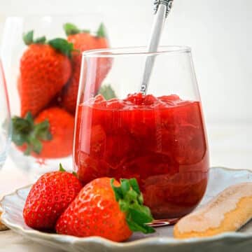 Strawberry rhubarb sauce in stemless wine glass with spoon.