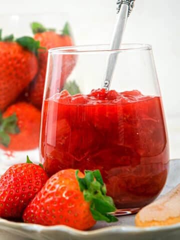 Strawberry rhubarb sauce in stemless wine glass with spoon.