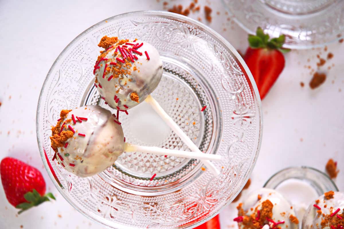 Strawberry cake pops on clear glass plate.