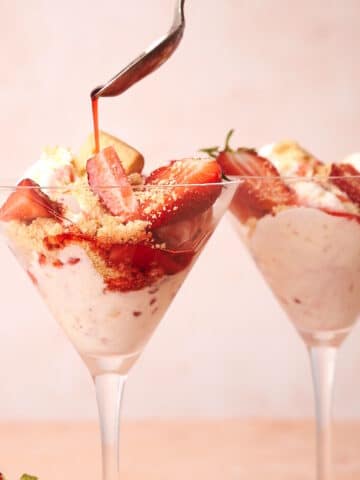 Strawberry shortcake ice cream in martini glasses with syrup pouring out of spoon.