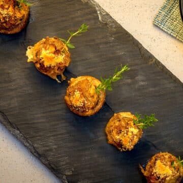 Stuffed button mushrooms on black serving tray.