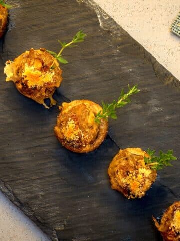 Stuffed button mushrooms on black serving tray.