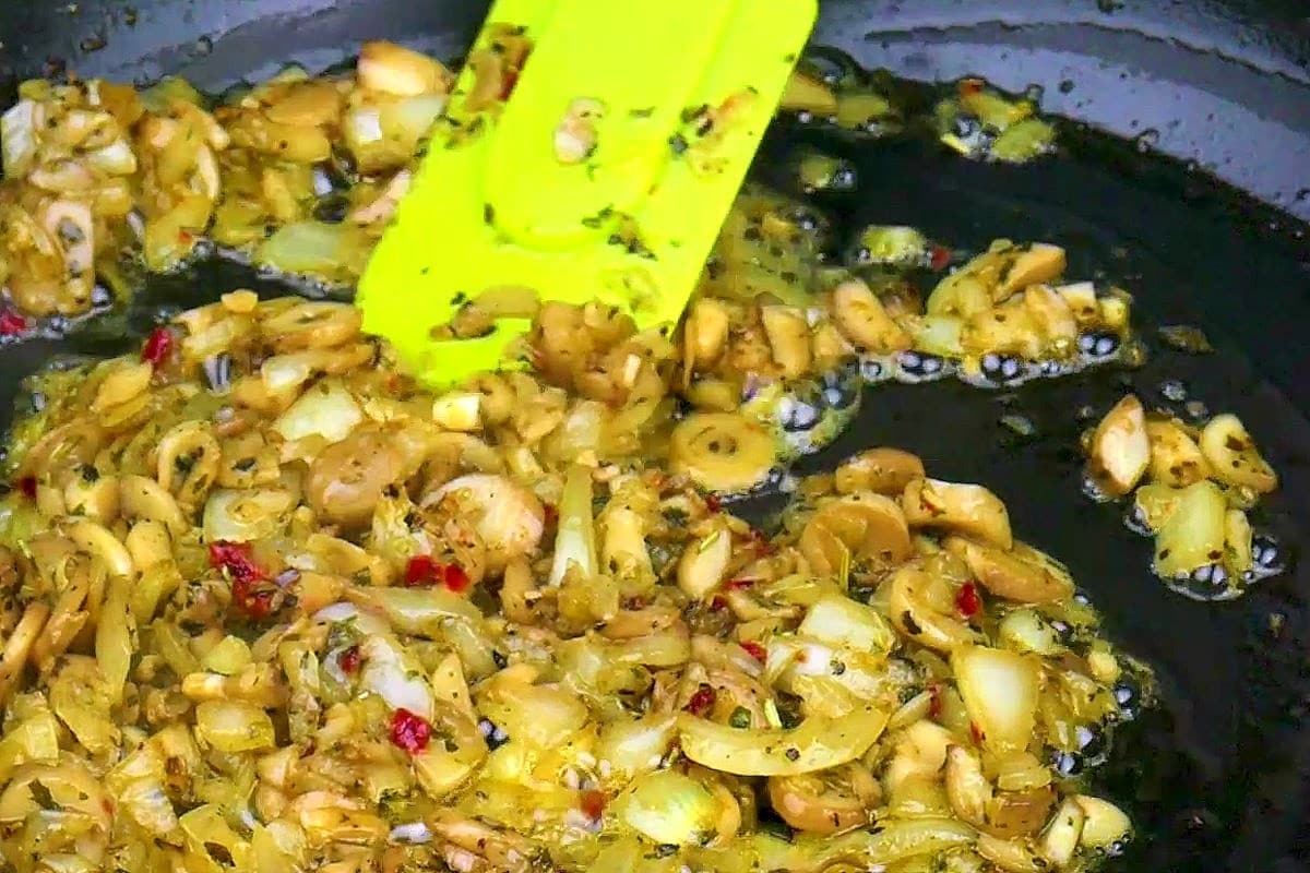 Mushrooms and onion filling cooking in pan.