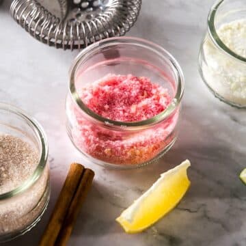 Three sugar rims in small glass jars on marble background.
