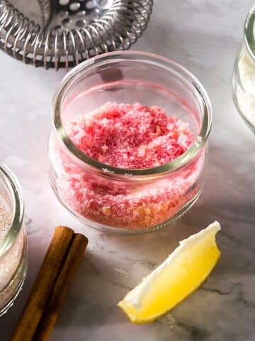 Three sugar rims in small glass jars on marble background.