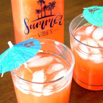 Summer mango pomegranate soda in glasses with blue umbrellas.