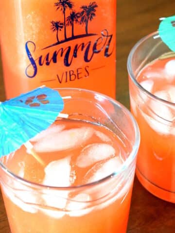 Summer mango pomegranate soda in glasses with blue umbrellas.